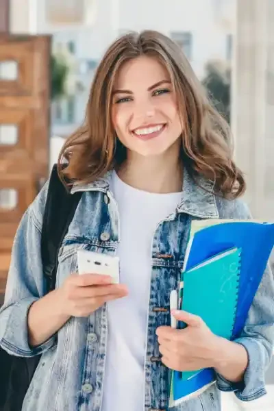 Studentă zâmbitoare cu telefon și cărți